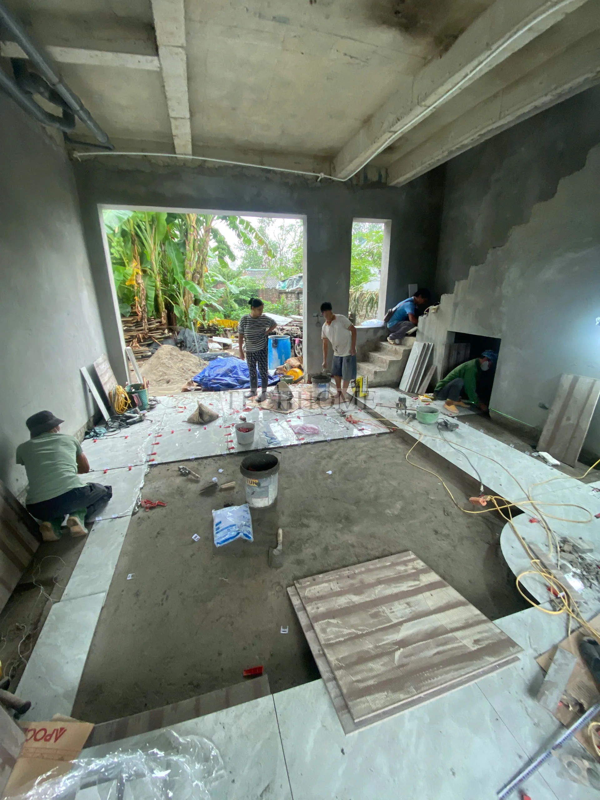 Đội ngũ thợ Techhome đang lát nền phòng khách bằng gạch vân đá sang trọng.